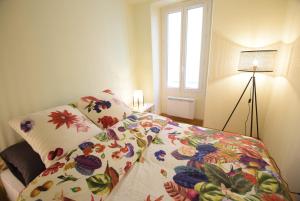 een slaapkamer met een bed met een bloemendeken en een raam bij Nice Renting - PAIROLIERE - SPACIOUS FLAT - OLD NICE - MASSENA - TERRACE in Nice
