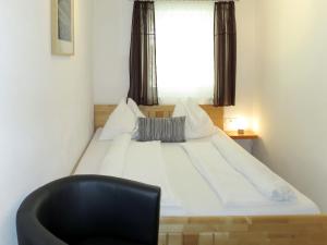 een slaapkamer met een bed met een zwarte stoel en een raam bij Apartment Hanser - MHO752 by Interhome in Ramsau im Zillertal