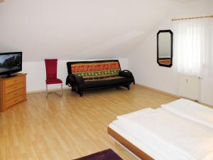 Apartment Glowe - GLW654 by Interhome في Klein Gelm: غرفة نوم مع أريكة وتلفزيون وكرسي