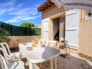 une table et des chaises blanches devant une maison dans l'établissement Holiday Home Les Villas de l'Aygual by Interhome, à Saint Cyprien Plage