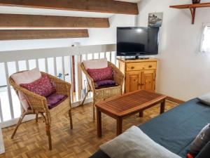 a living room with two chairs and a tv at Holiday Home Les Marines des Capellans by Interhome in Saint-Cyprien-Plage