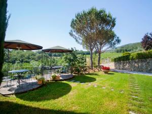 een tuin met twee picknicktafels en parasols bij Apartment Lucia by Interhome in Podere Panzano