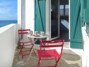 2 rote Stühle und ein Tisch auf einer Veranda in der Unterkunft Holiday Home Les Roches - LPU 103 by Interhome in Clohars-Carnoët