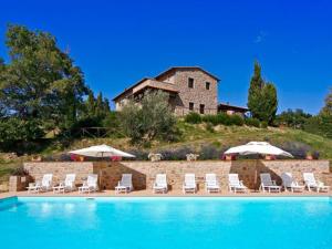 a pool with chairs and umbrellas and a house at Holiday Home Podere dei Venti by Interhome in Leccio