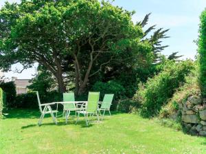 een tafel en stoelen in een tuin met een boom bij Holiday Home Ty Angèle - PLC239 by Interhome in Plouescat
