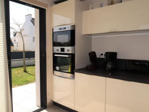 a kitchen with white cabinets and a microwave oven at Holiday Home Ty Pleine - GUL101 by Interhome in Le Guilvinec