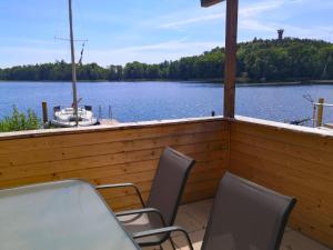 eine Veranda mit Stühlen und einem Boot auf einem See in der Unterkunft Chalet Güstrower Chaussee by Interhome in Krakow am See