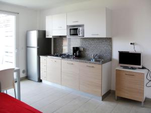 uma cozinha com armários brancos e um frigorífico em Apartment Fiore-2 by Interhome em Lignano Sabbiadoro
