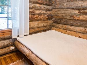 a bed in a log cabin with a window at Holiday Home Retkietappi honkapirtti by Interhome in Juuma