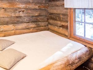 a bed in a log cabin with a window at Holiday Home Retkietappi kelopirtti by Interhome in Juuma