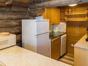 einen weißen Kühlschrank in einer Küche mit Holzwänden in der Unterkunft Holiday Home Retkietappi kelopirtti by Interhome in Juuma