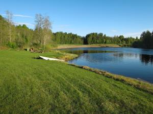 a river with a boat in the middle of a field at Chalet Höje - VMD220 by Interhome in Hagfors