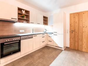 a kitchen with white cabinets and a wooden door at Apartment Michi by Interhome in Schwendau