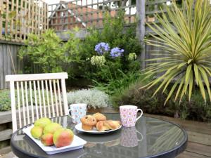 a glass table with two plates of fruit and cups at Holiday Home Alde End by Interhome in Snape