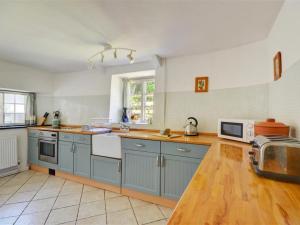 a large kitchen with blue cabinets and a microwave at Holiday Home Blisland by Interhome in Blisland