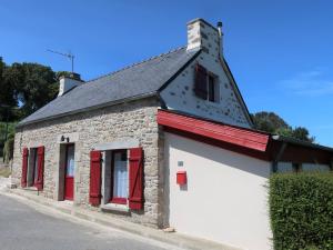 un piccolo edificio in pietra con finestre rosse e tetto nero di Holiday Home La Charmeuse - GOV203 by Interhome a Goulven