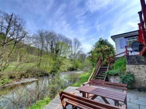 a wooden bench sitting next to a river at Holiday Home Pantperthog by Interhome in Esgair-geiliog