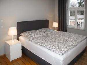 ein Bett mit einer schwarzen und weißen Bettdecke und zwei Lampen in der Unterkunft Apartment Villa am Meer by Interhome in Lubmin