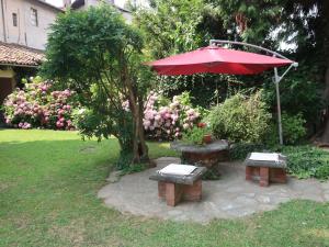 San Giorgio CanaveseにあるApartment Appartamento del Castello by Interhomeの庭の赤傘と二つのベンチ