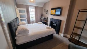 a bedroom with a bed with white sheets and a television at The Bold Arms Hotel in Beaumaris