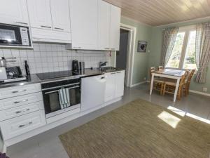 eine Küche mit weißen Schränken und einem Tisch mit einem Esszimmer in der Unterkunft Holiday Home Tallbacka by Interhome in Bromary