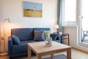 un soggiorno con un divano blu e un tavolo di Haus Nordseegruss, App 4 a Wenningstedt