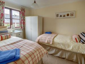 a bedroom with two beds and a white refrigerator at Holiday Home Valentines Cottage by Interhome in Braunton