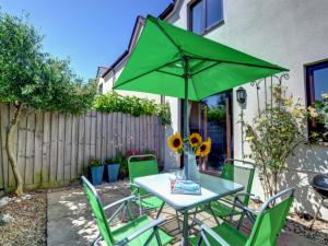 a table and chairs with a green umbrella at Holiday Home Valentines Cottage by Interhome in Braunton