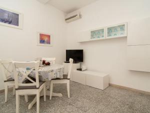Ein weißes Zimmer mit einem Tisch und Stühlen sowie einem TV. in der Unterkunft Apartment Carlino by Interhome in Nerano