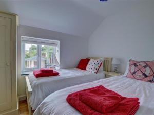 a bedroom with two beds with red blankets on them at Holiday Home Watery Lane by Interhome in Croyde
