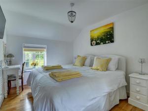 a bedroom with a large white bed with yellow pillows at Holiday Home Watery Lane by Interhome in Croyde