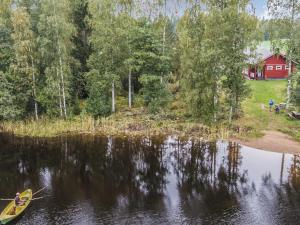 a person in a boat on a lake with a red house at Holiday Home Kuikanranta by Interhome in Hara