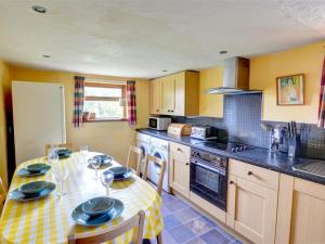 una cocina con mesa y sillas y una cocina con paredes amarillas. en Holiday Home Maes-yr-Helmau by Interhome, en Dolgellau
