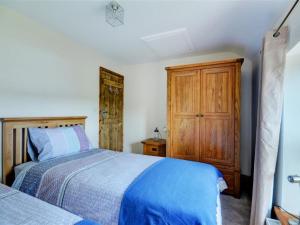 カムボーンにあるHoliday Home Pendarves by Interhomeのベッドルーム1室(ベッド2台、木製キャビネット付)