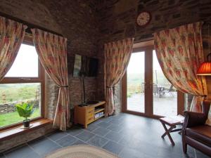 LlanbrynmairにあるHoliday Home Uwch y Foel by Interhomeの窓付きのリビングルーム、ソファ、時計が備わります。