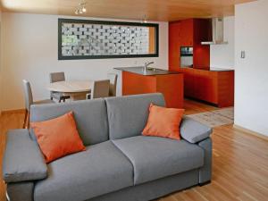 a living room with a gray couch with orange pillows at Chalet Le Raccard by Interhome in Savièse