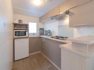 uma cozinha com armários brancos e um micro-ondas em Holiday Home Park Kerlinga-18 by Interhome em Bredene