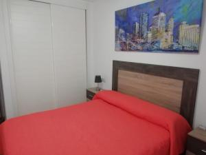 Un dormitorio con una cama roja y una pintura en la pared en Apartamento naturista Vera Playa, en Vera