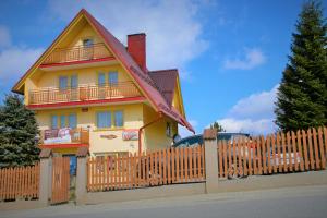 a yellow house with a wooden fence in front of it at Pokoje Gościnne Janina Bocheńczak in Gliczarów