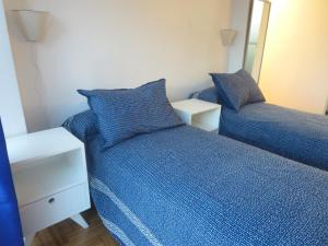 1 dormitorio con 2 camas con sábanas azules y espejo en Obelisco Studio 9 en Buenos Aires