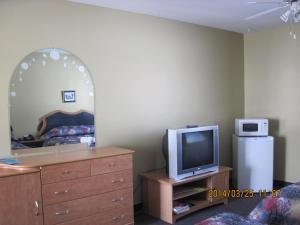 a bedroom with a dresser and a mirror and a tv at Motel Parc Beaumont Inc. in Beaumont