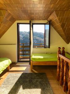 a bedroom with two beds and a large window at Vikend kuća Čairović in Kopaonik