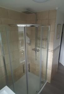 a shower with a glass door in a bathroom at Moore Apartment in Bourton on the Water