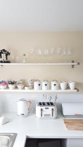 a kitchen counter with glasses and dishes on shelves at Moore Apartment in Bourton on the Water