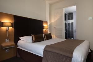 Schlafzimmer mit einem großen Bett mit einem schwarzen Kopfteil in der Unterkunft Hotel Restaurant du Centre et du Lauragais in Castelnaudary