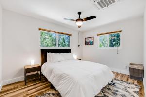 ein weißes Schlafzimmer mit einem Bett und zwei Fenstern in der Unterkunft Lily Haus in Idyllwild