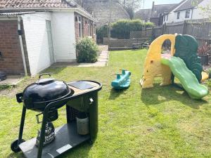 a backyard with a grill and a childs play equipment at Coastline Retreats - Cosy Bungalow in Ringwood Town Centre with lots of Parking and Large Enclosed Garden in Ringwood