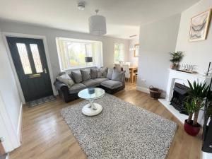 a living room with a couch and a table at Coastline Retreats - Cosy Bungalow in Ringwood Town Centre with lots of Parking and Large Enclosed Garden in Ringwood