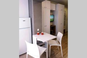uma cozinha com uma mesa e cadeiras brancas e um frigorífico em Квартира студия посуточно Южный вокзал 5 минут em Kharkov