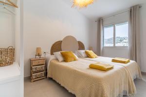 a white bedroom with a large bed with yellow pillows at Finca Jacinto in Sayalonga +22 photos